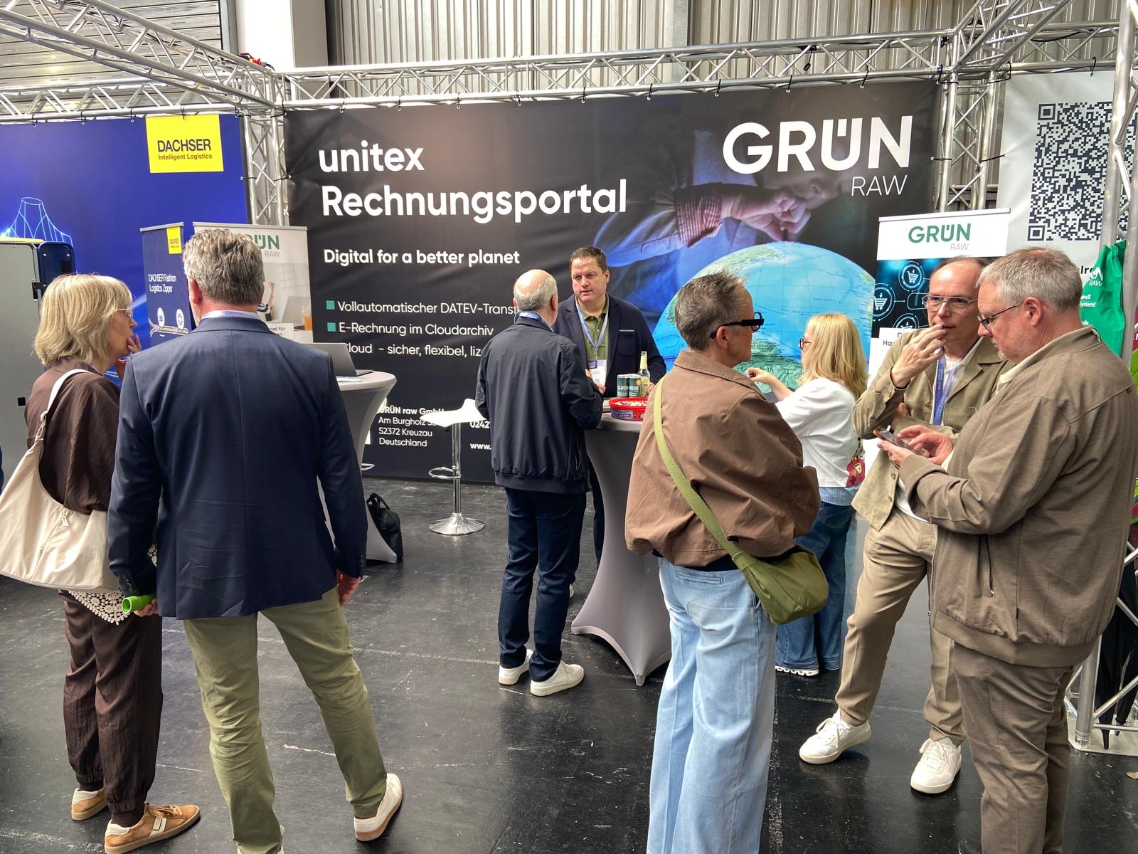 Messestand der GRÜN raw auf dem unitex FASHION FESTIVAL mit Rechnungsportal, Rollups und Stehtischen