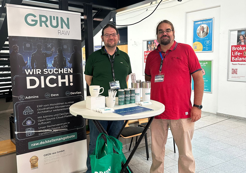 Zwei Mitarbeiter der GRÜN raw stehen am Messestand auf der FrOSCon 21.